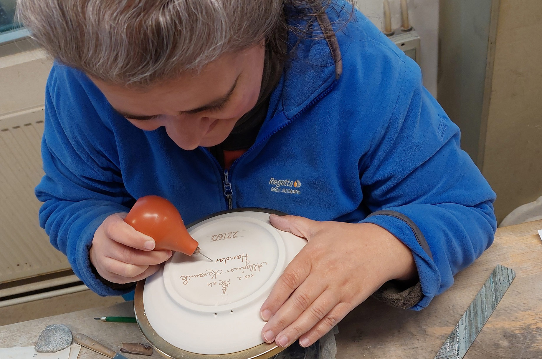 Hotels und Ferienwohnungen im Oberallgäu - Gutscheine - Allgäuer Keramik in Altstädten im Allgäu
Die Malerin beschriftet einen Teller - Allgäuer Keramik in Altstädten